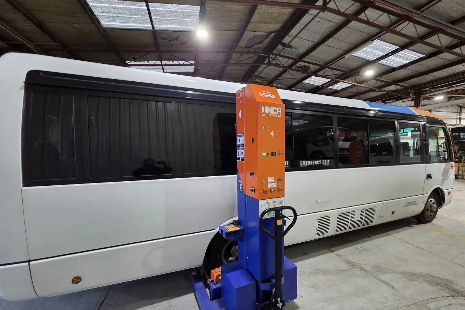 A coach lifted clear of the floor on a mobile column lift