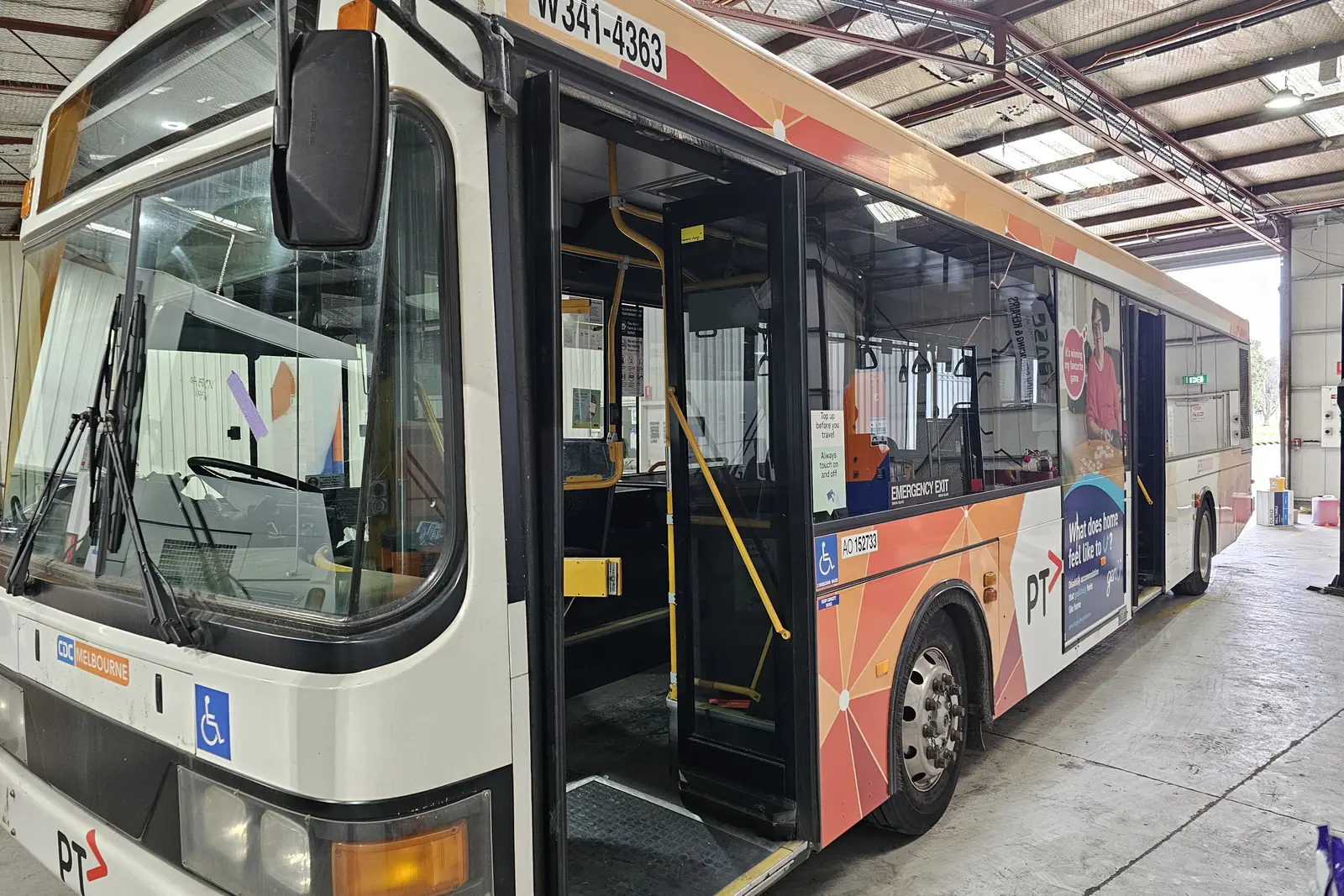 The front of a route bus in the workshop with its passenger doors open