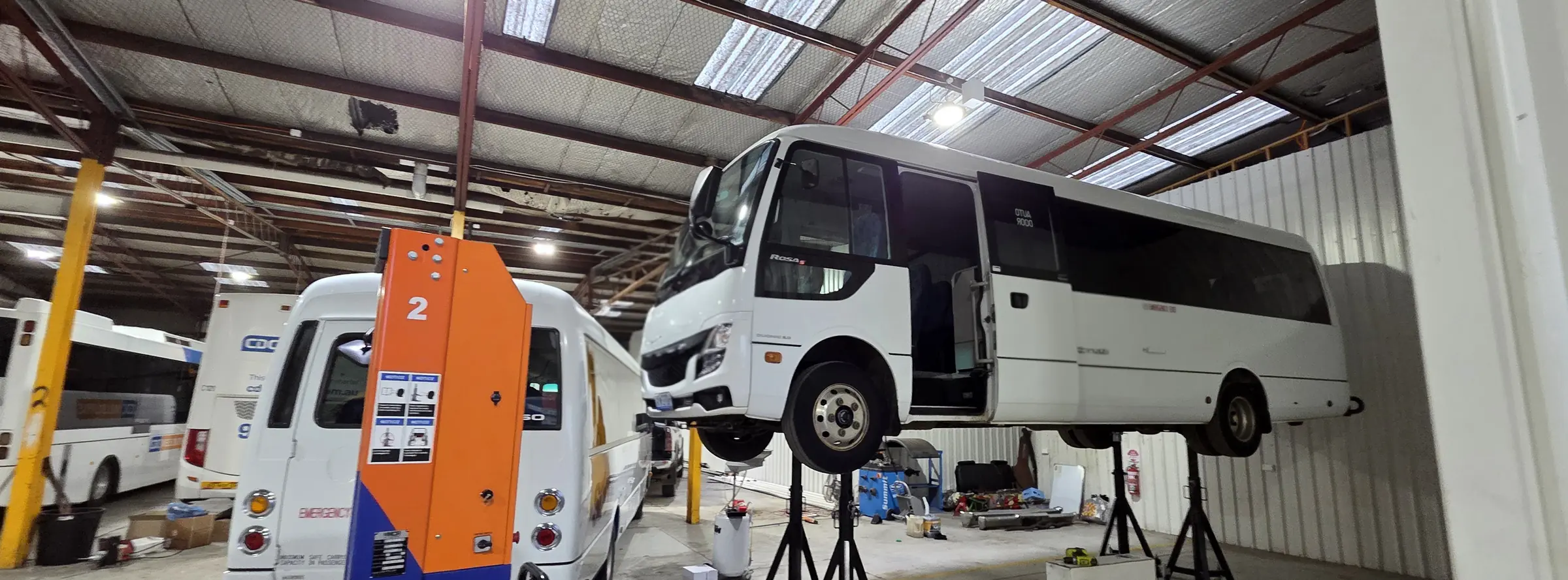 Fleet coaches raised on mobile column lifts across the workshop floor
