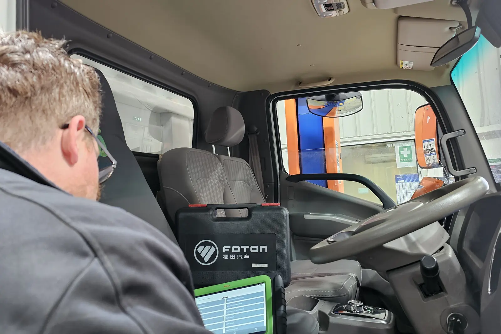 A technician running a diagnostic scan from the driver’s seat of a Foton truck