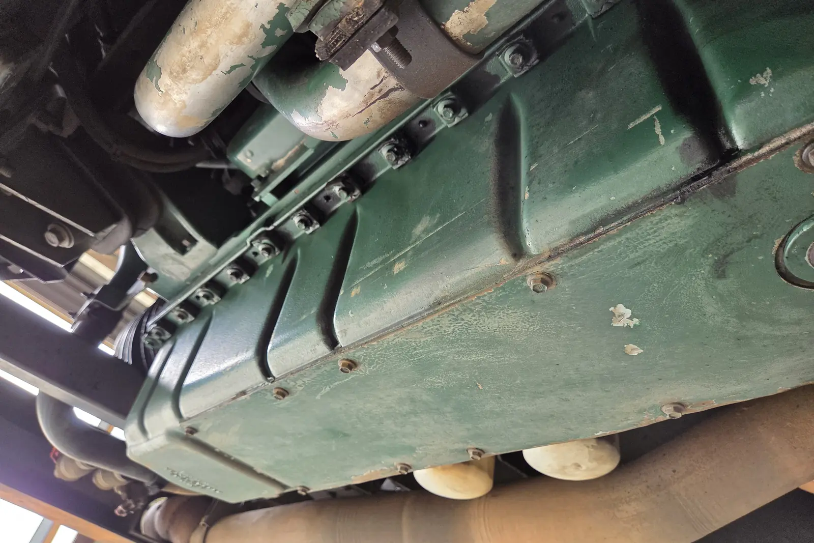 Close-up of a diesel engine sump and exhaust pipes beneath a raised vehicle