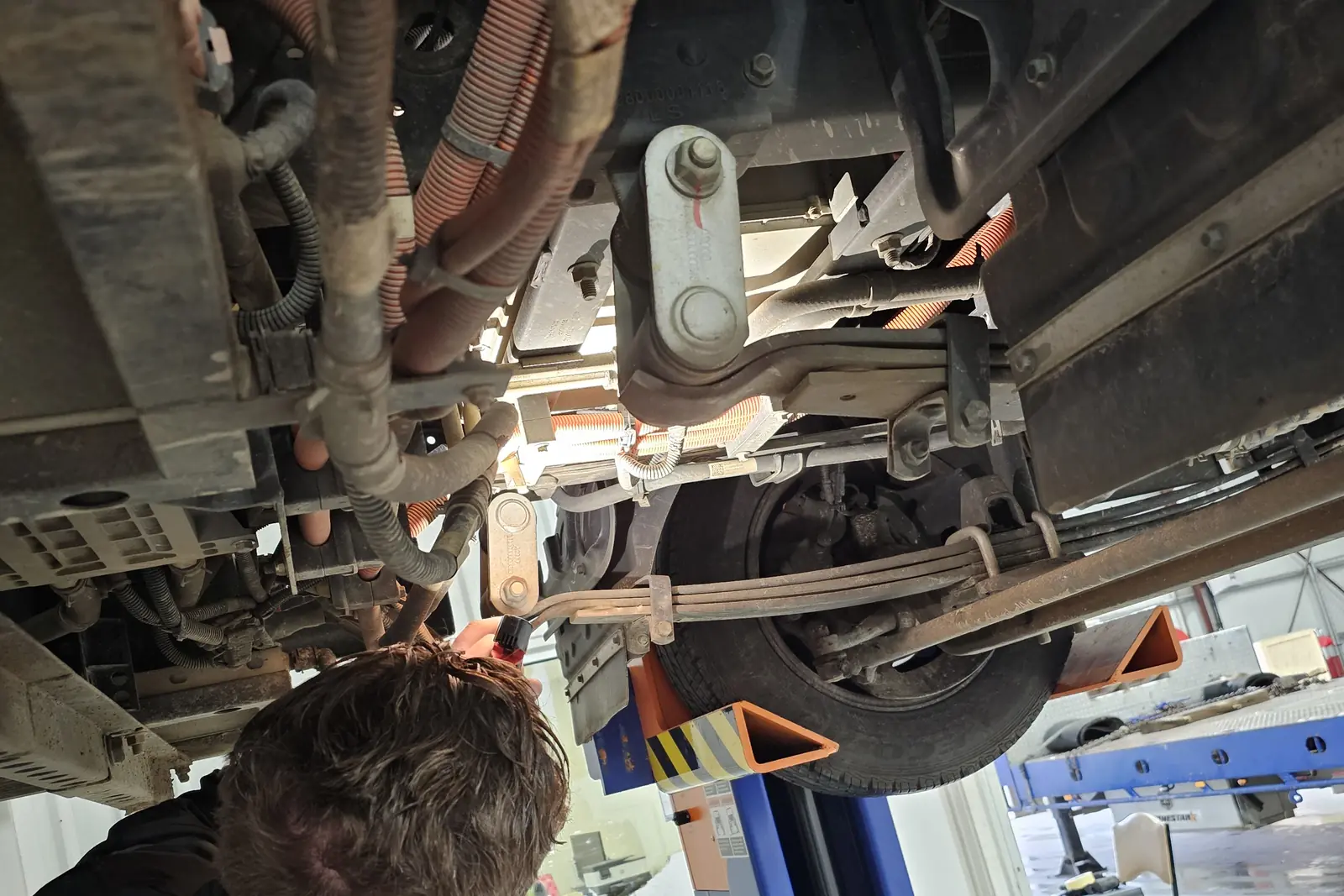 Close-up of a heavy vehicle front suspension, steering linkage and brake components, seen from below